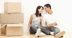 Young couple affectionately sit on the floor together next to some moving boxes.